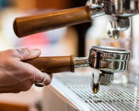 A barista putting a portafilter into an espresso machine group