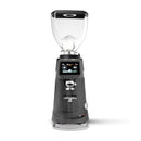 A professional electric coffee grinder with a dark gray body, clear hopper, and digital touch screen interface, shown on a solid white background.