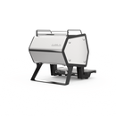 A sleek, modern outdoor camping stove with a silver metallic body and black structural legs, shown on a solid white background.