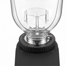 A close-up of a clear glass jar with a black base and a silver metal dial ring on a white background.