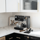 Black Ascaso espresso machine on a kitchen counter with a magazine and coffee cups.