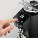 Hand pressing a button on a coffee grinder with a digital display